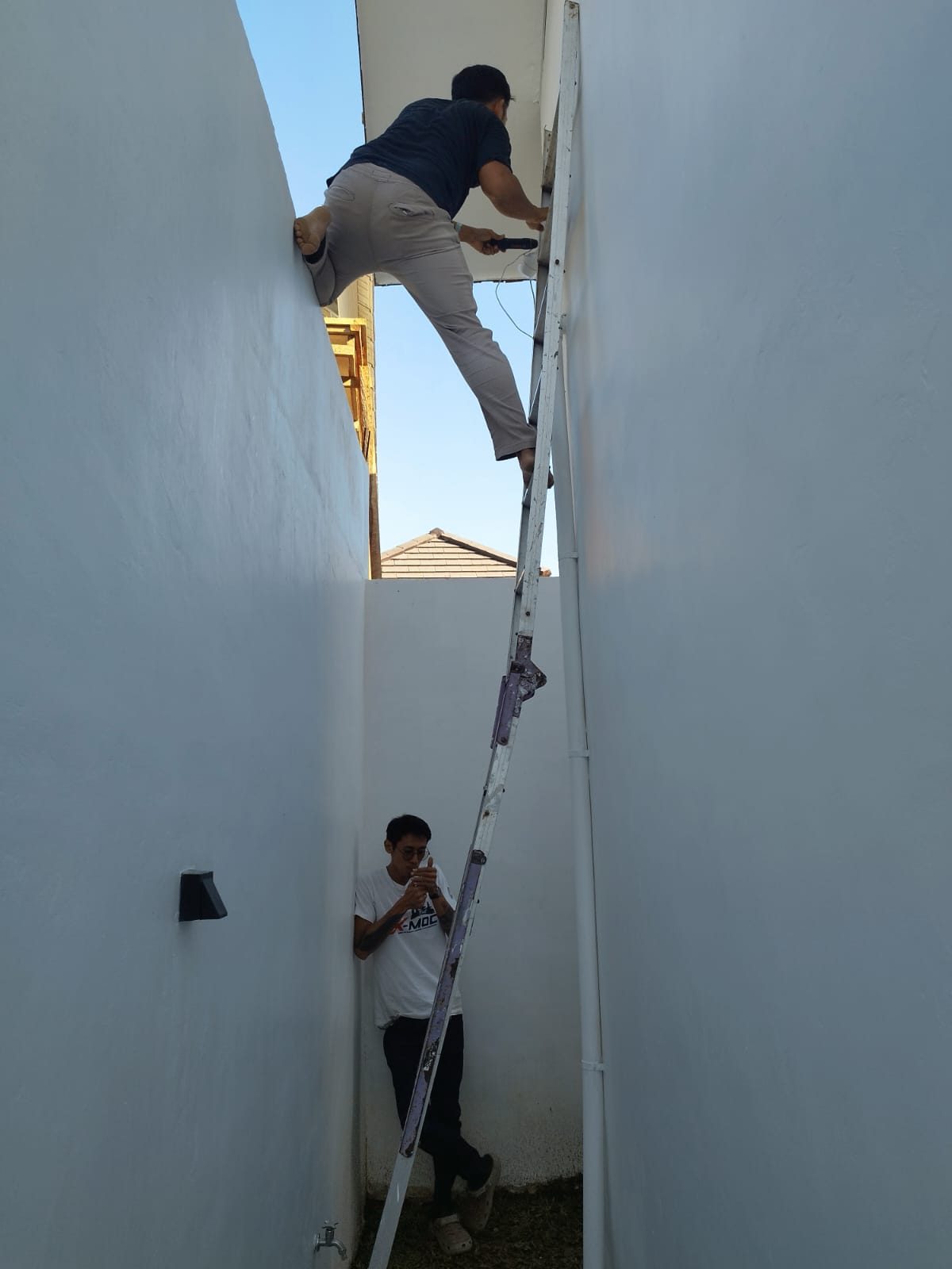 Sanjaya and a trusted technician running cable between two villa walls